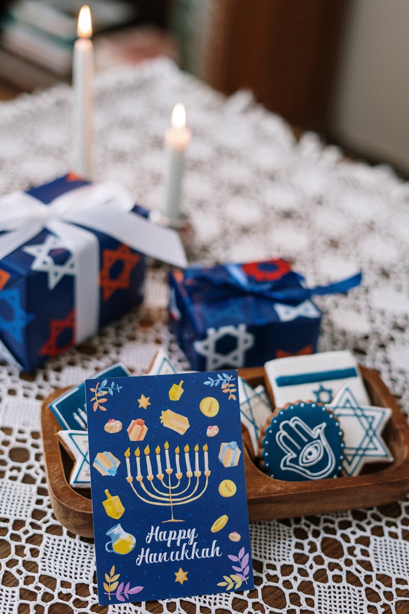 Close-up of Hanukkah table setup with gifts, cookies, and candles on lace.