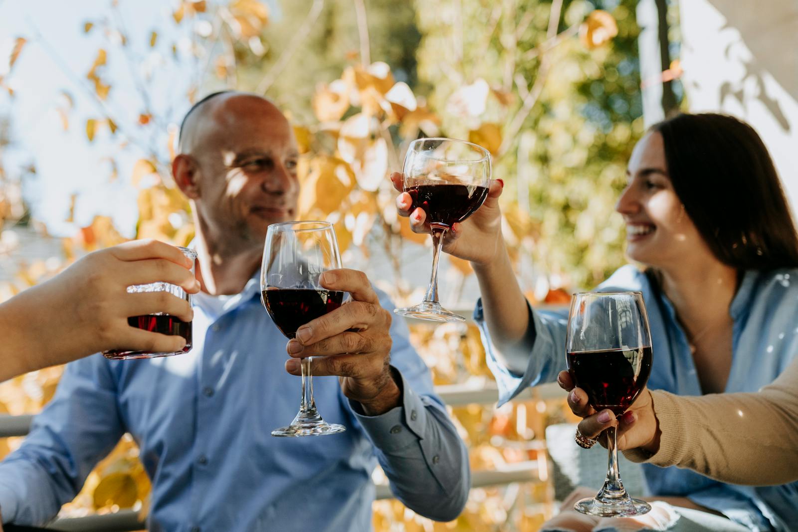 A cheerful group enjoying red wine outdoors in a festive celebration.